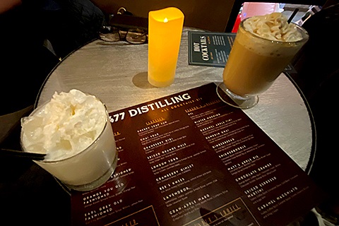 A drink menu sits next to a beverage at 477 Distilling